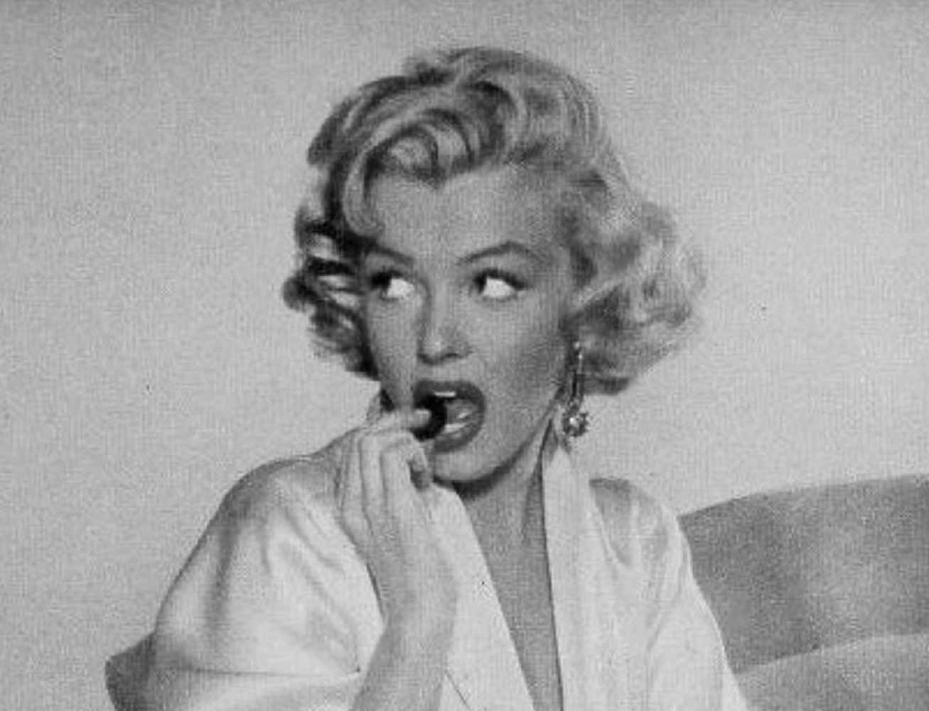 B&W portrait of Marilyn Monroe eating and looking at side - 1954