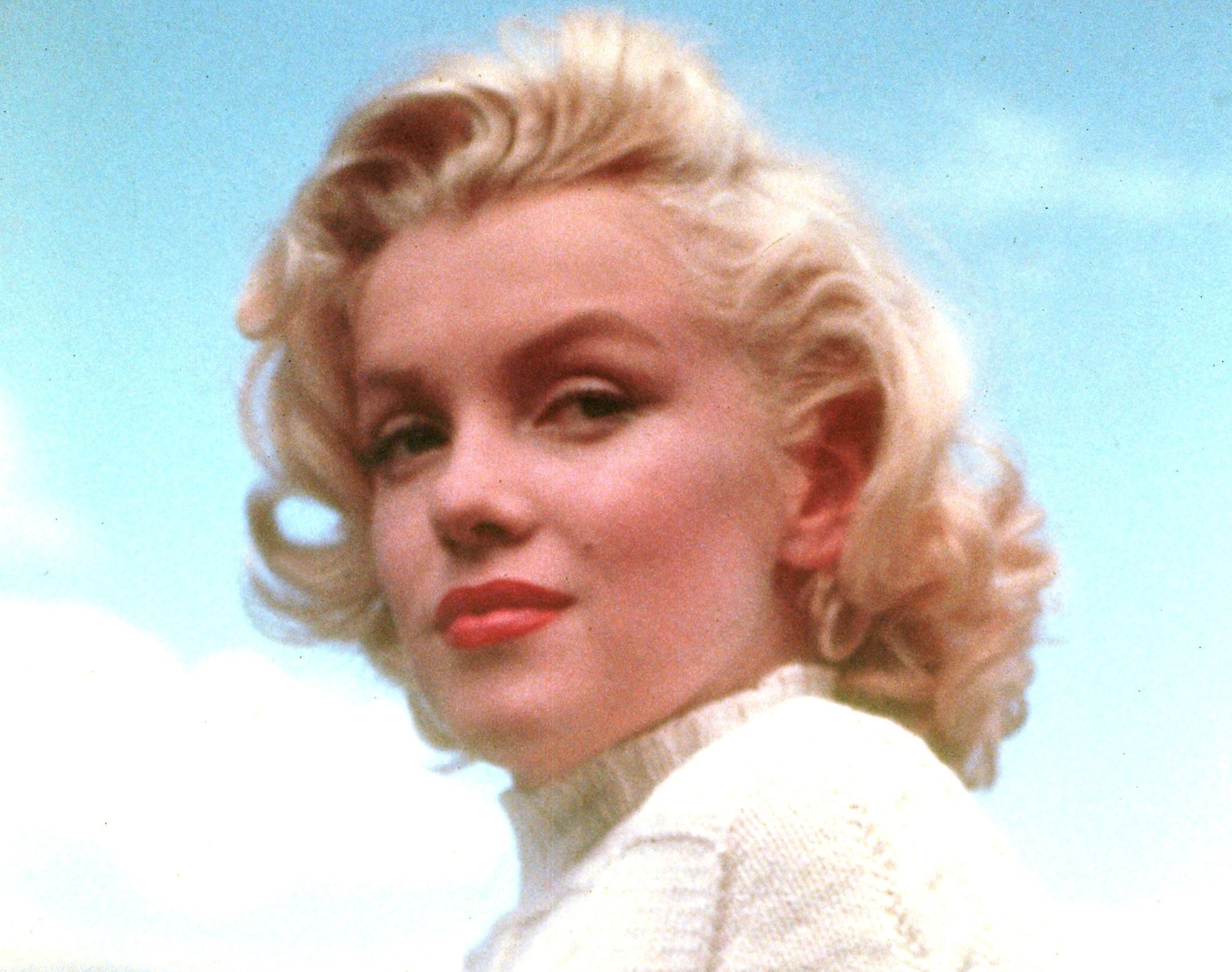 Marilyn Monroe wearing white sweater is looking at side and smiling - 1953
