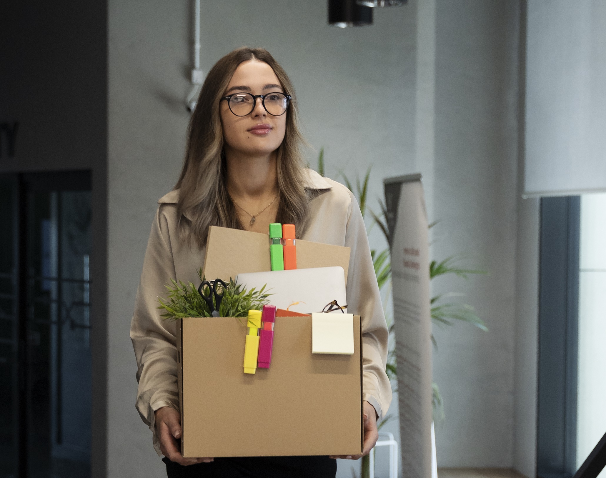 Young woman is holding box with her stuff and leaving.