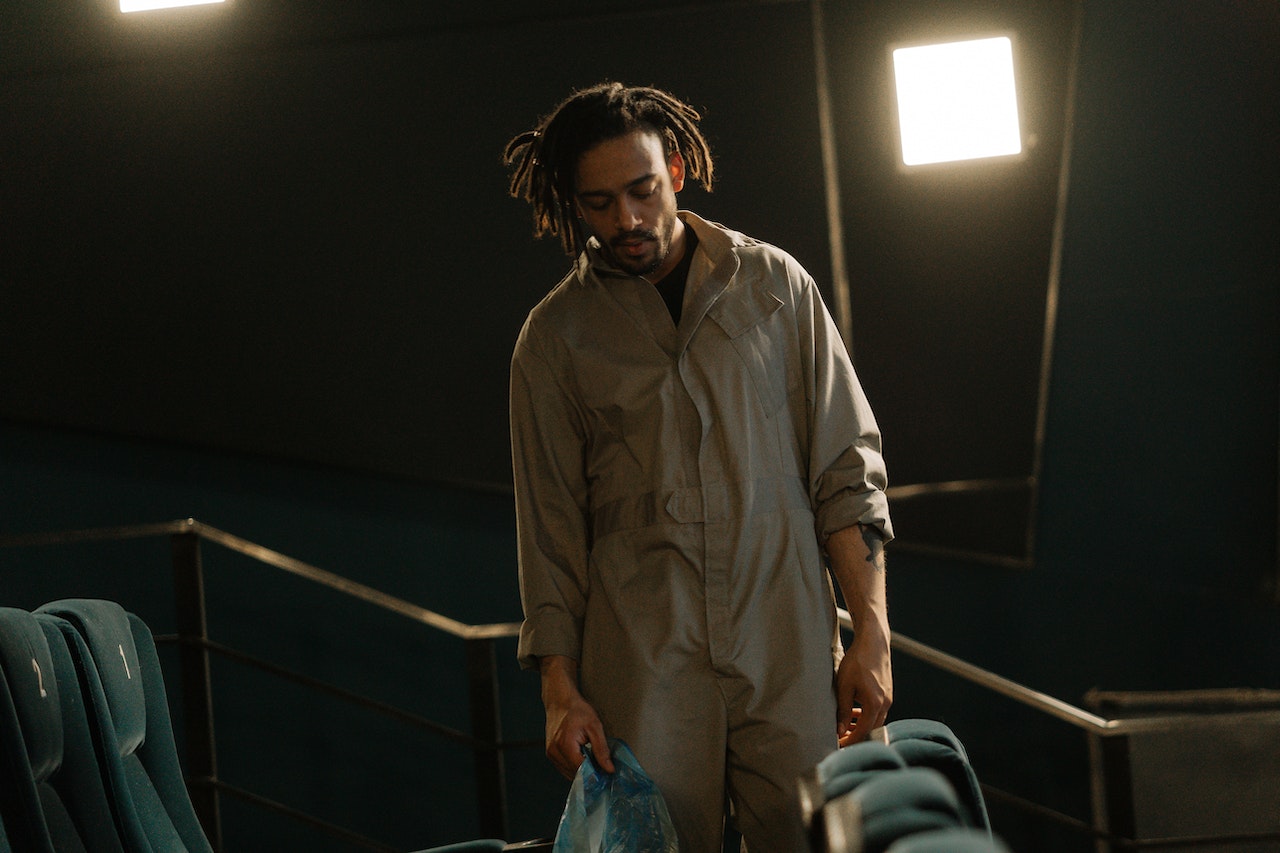 Young man wearing grey suit is working inside a movie theater.