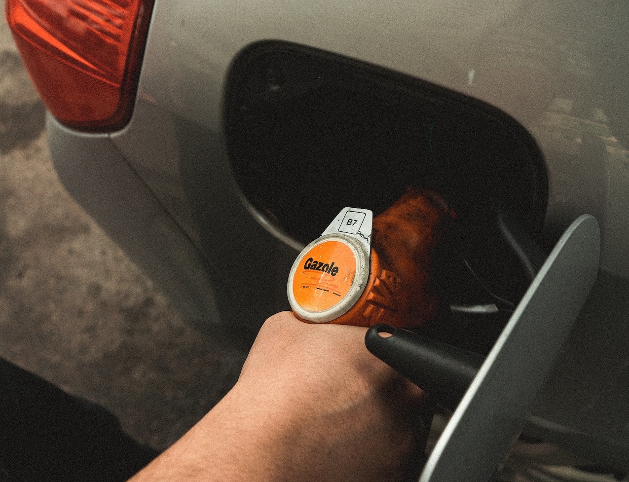 Man is filling gas tank with fuel at gas station.