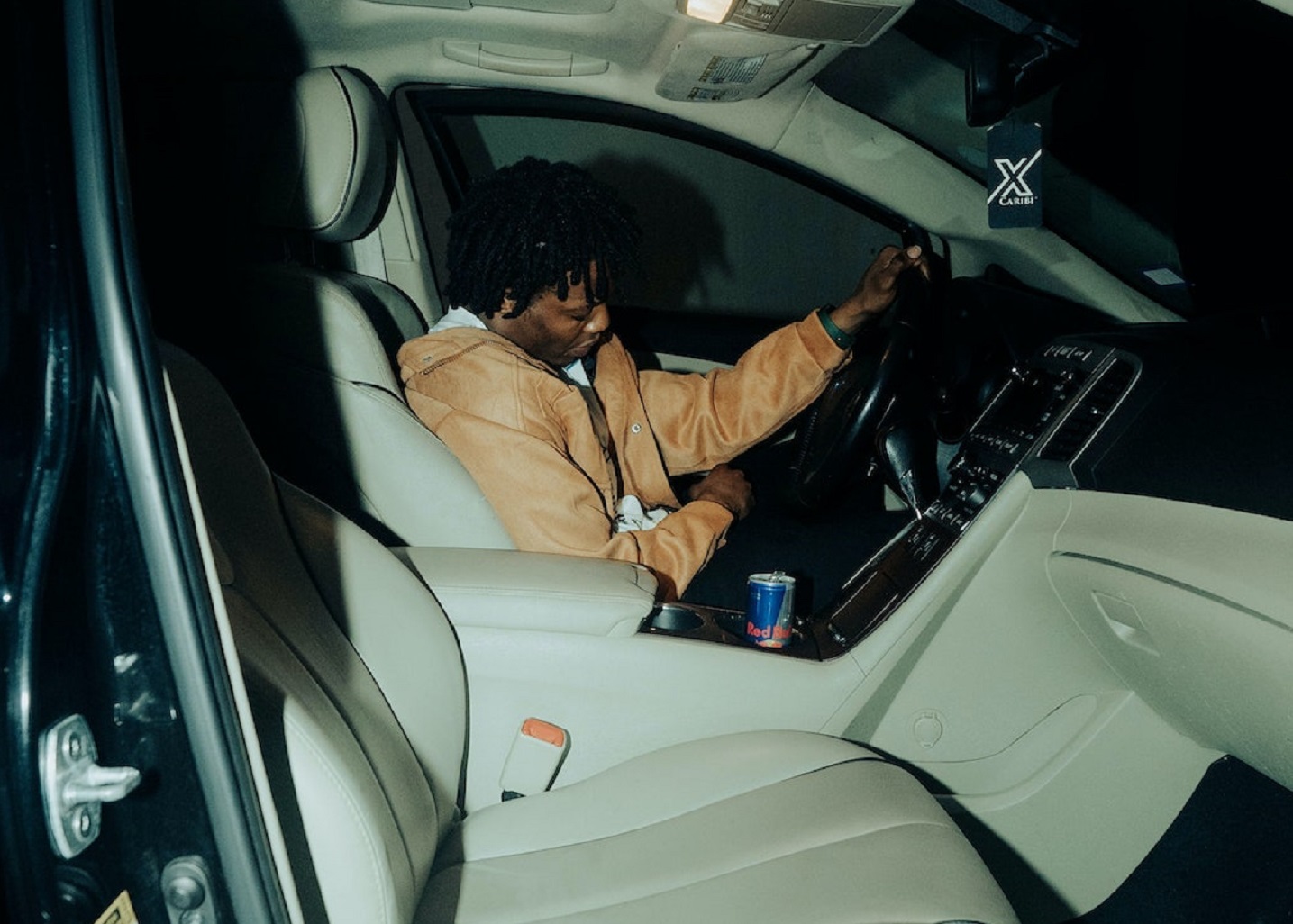 Man wearing brown jacket is sleeping on the seat in the car.