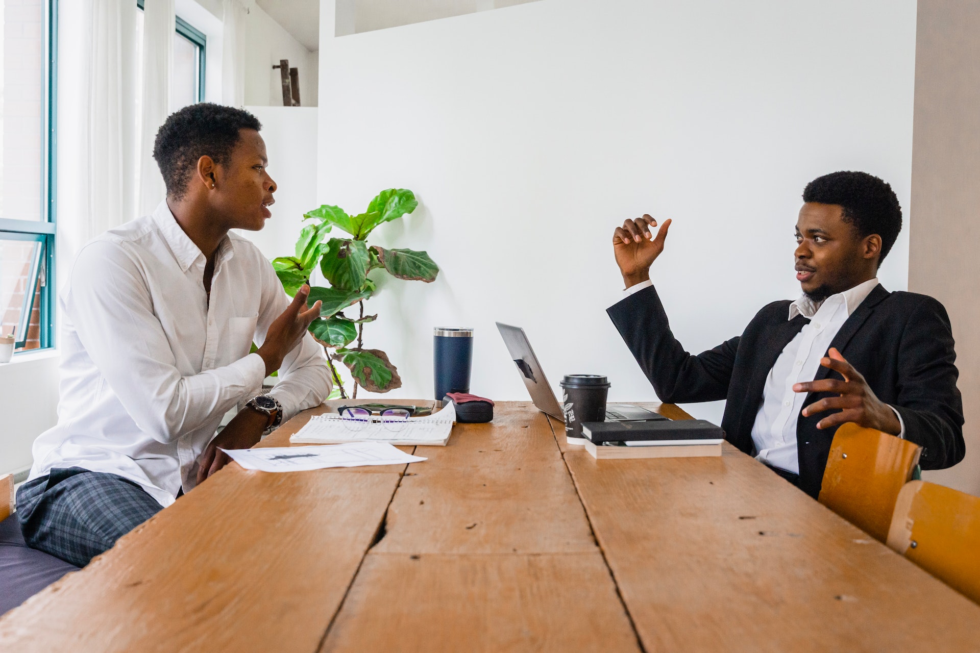 Two black men are talking to each other about business at office.