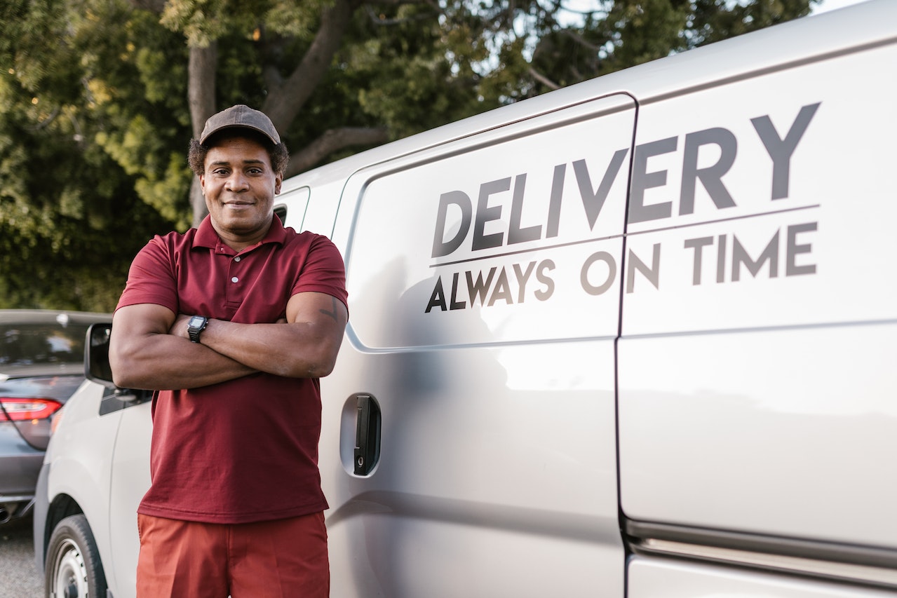 Man is standing and smiling next to a company van.