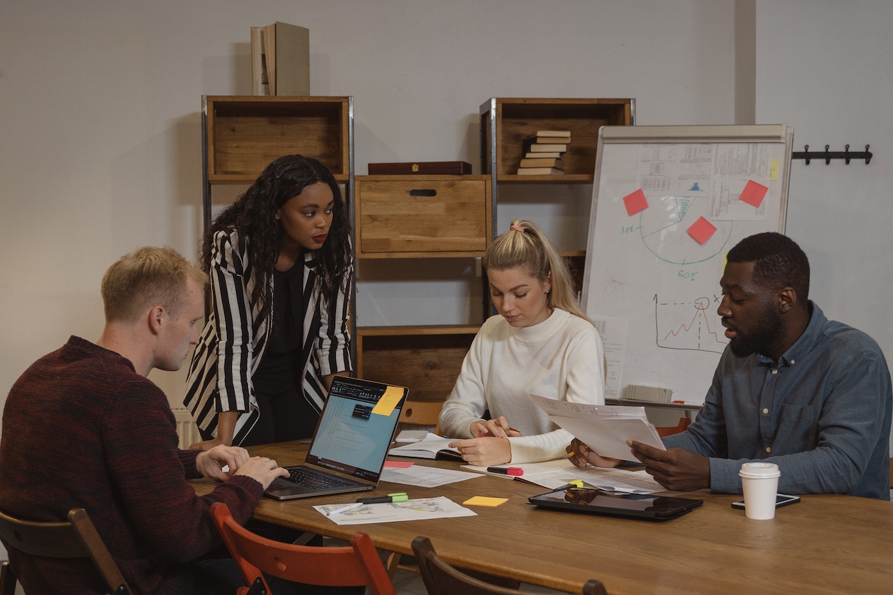Woman is holding a office meeting with co-workers in office.