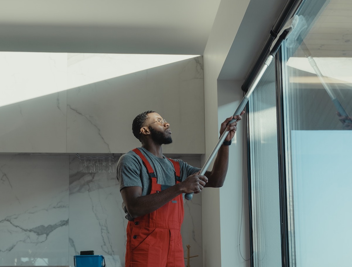 Young man is cleaning the windows.