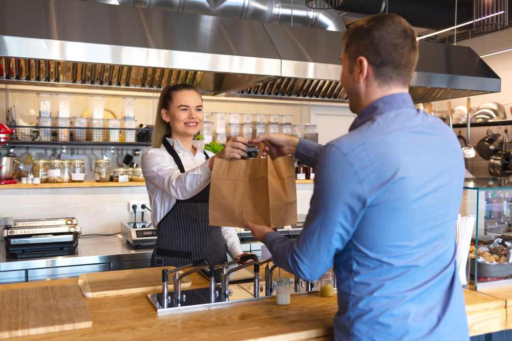 Cheerful waitress wearing apron serving customer