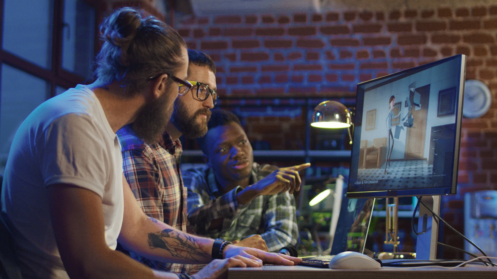 Side view of diverse group of men sitting at table with computer working on animation