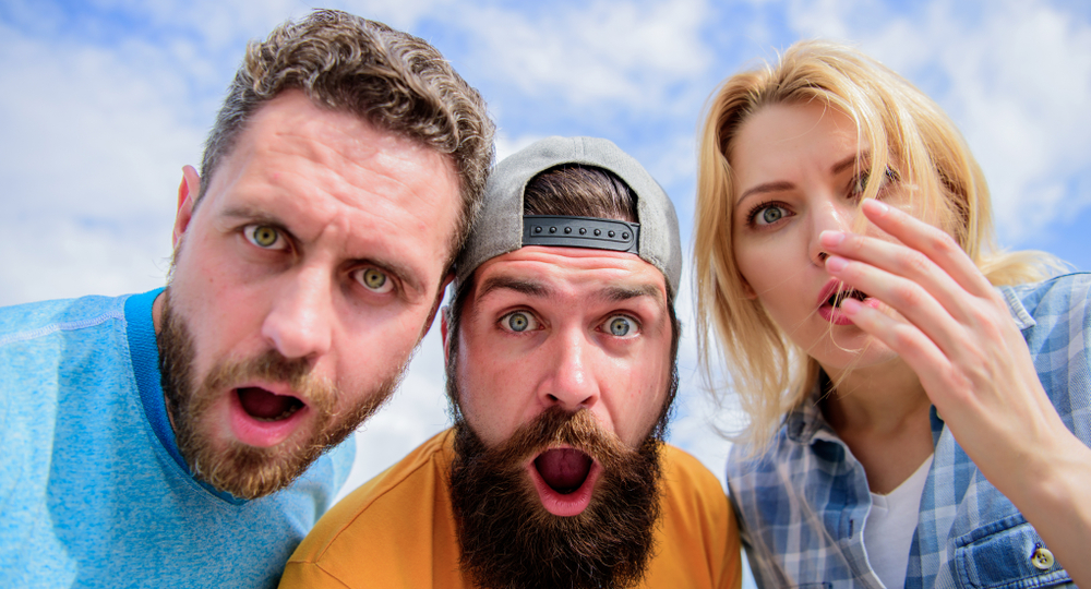 Three people looking shocked at the camera outside