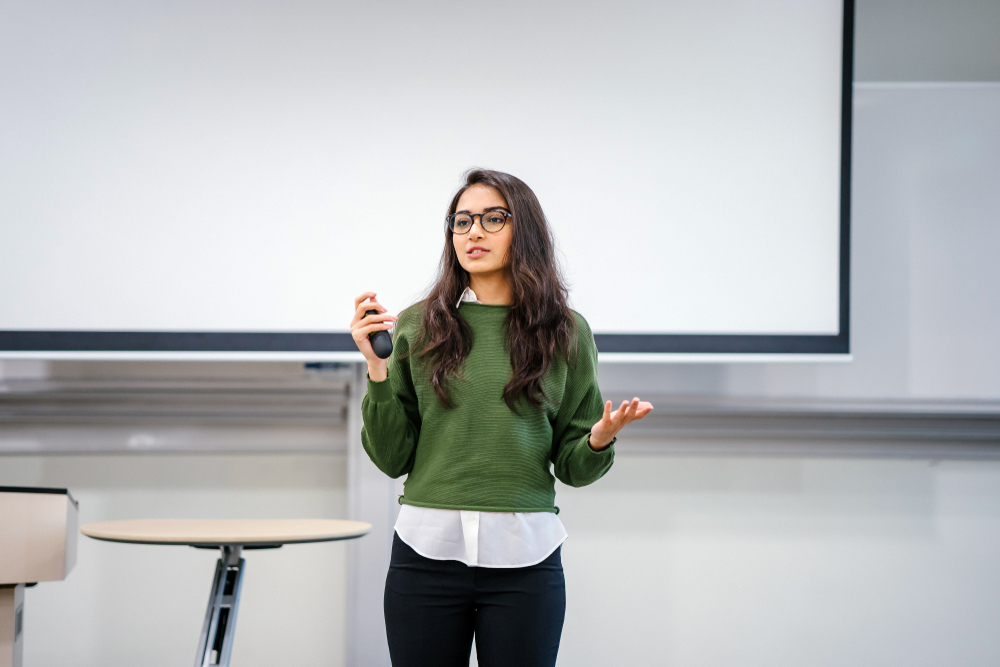 Girl in school giving a presentation in front of the class in green sweater