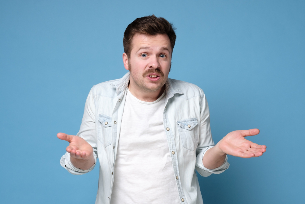 Handsome man with mustache looking questioned standing with spread hands , in denim shirt