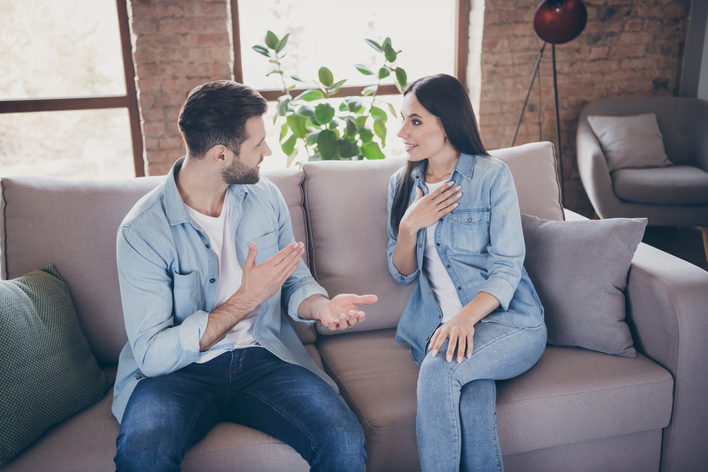 Shocked Man and woman having a conversation sitting on a couch in denim shirts
