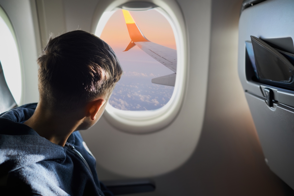 Caucasian boy looking into a plane window during a flight