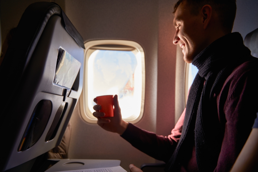 Smiling airline passenger with a paper cup of coffee