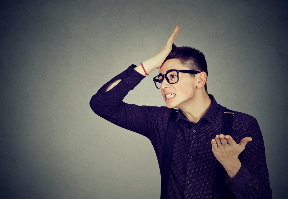 Silly young man, slapping his hand on head having duh moment, in black shirt