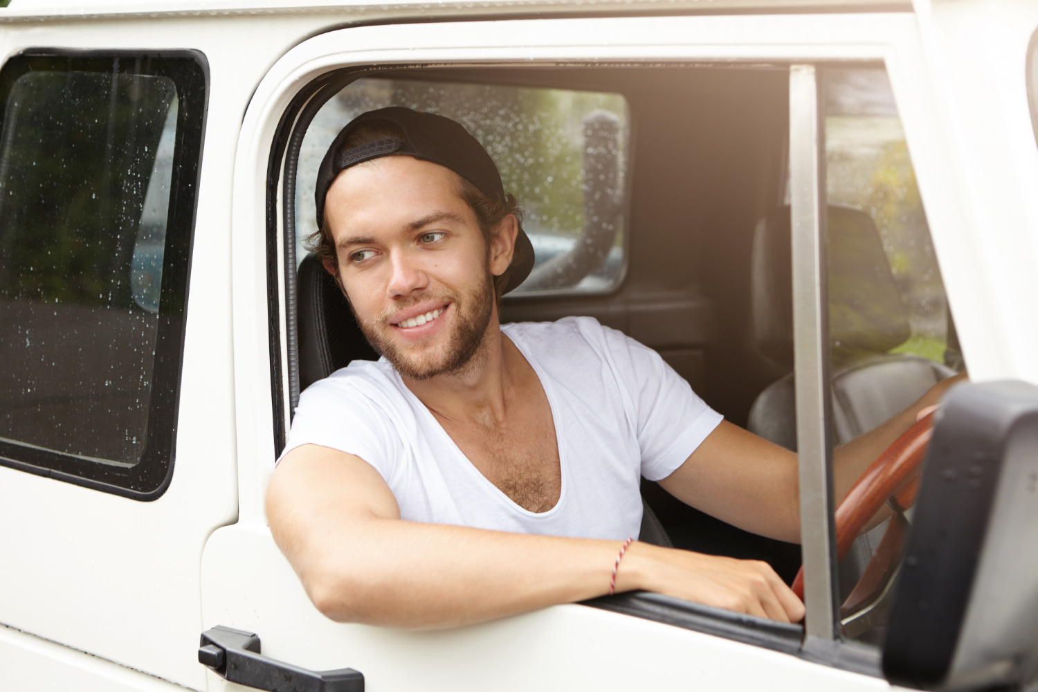 Young man is seating in his white pick up truck.
