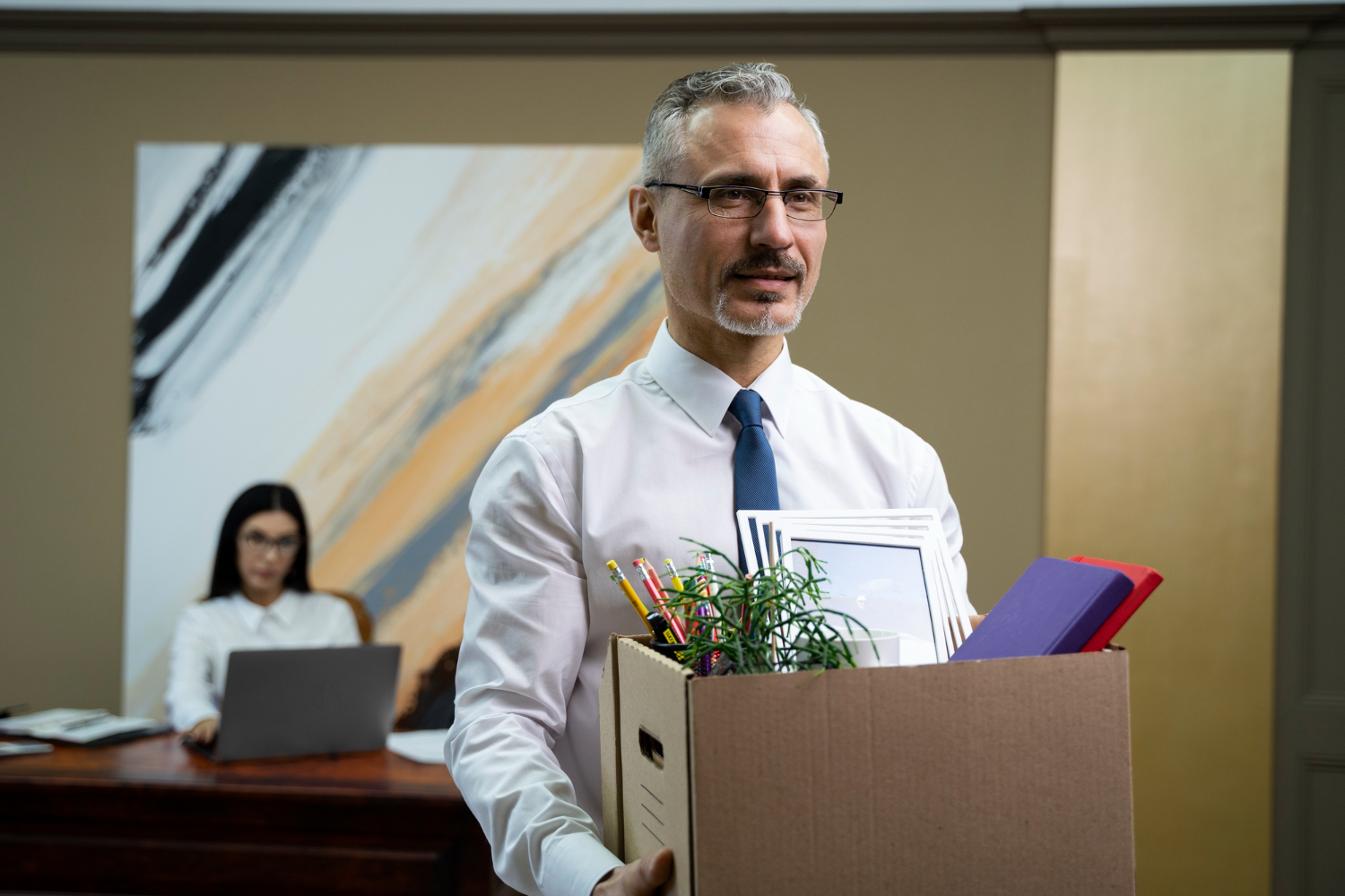 Man is holding a box with personal stuff after being fired from office.
