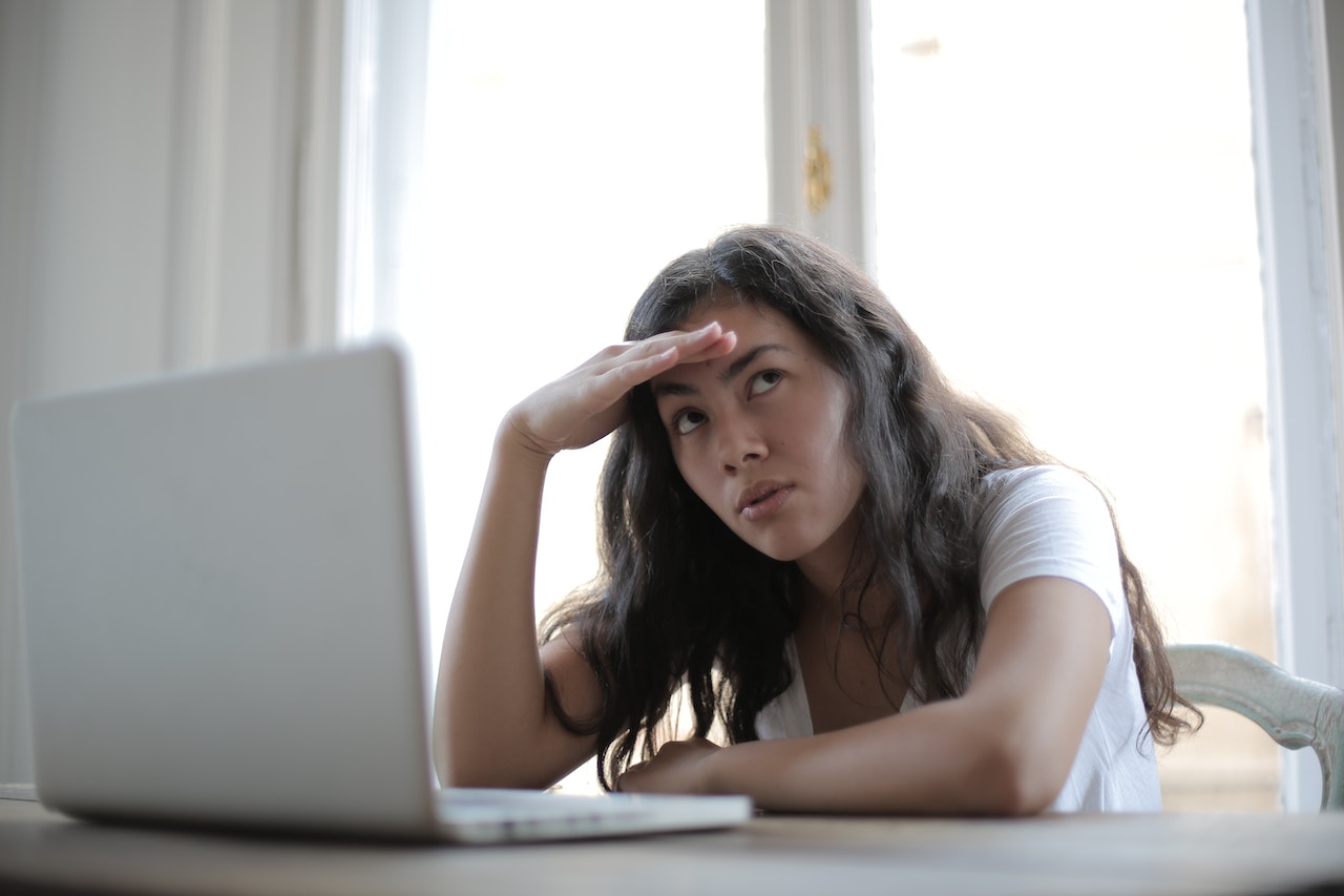 Girl is seating in front of a lap top with upset face.