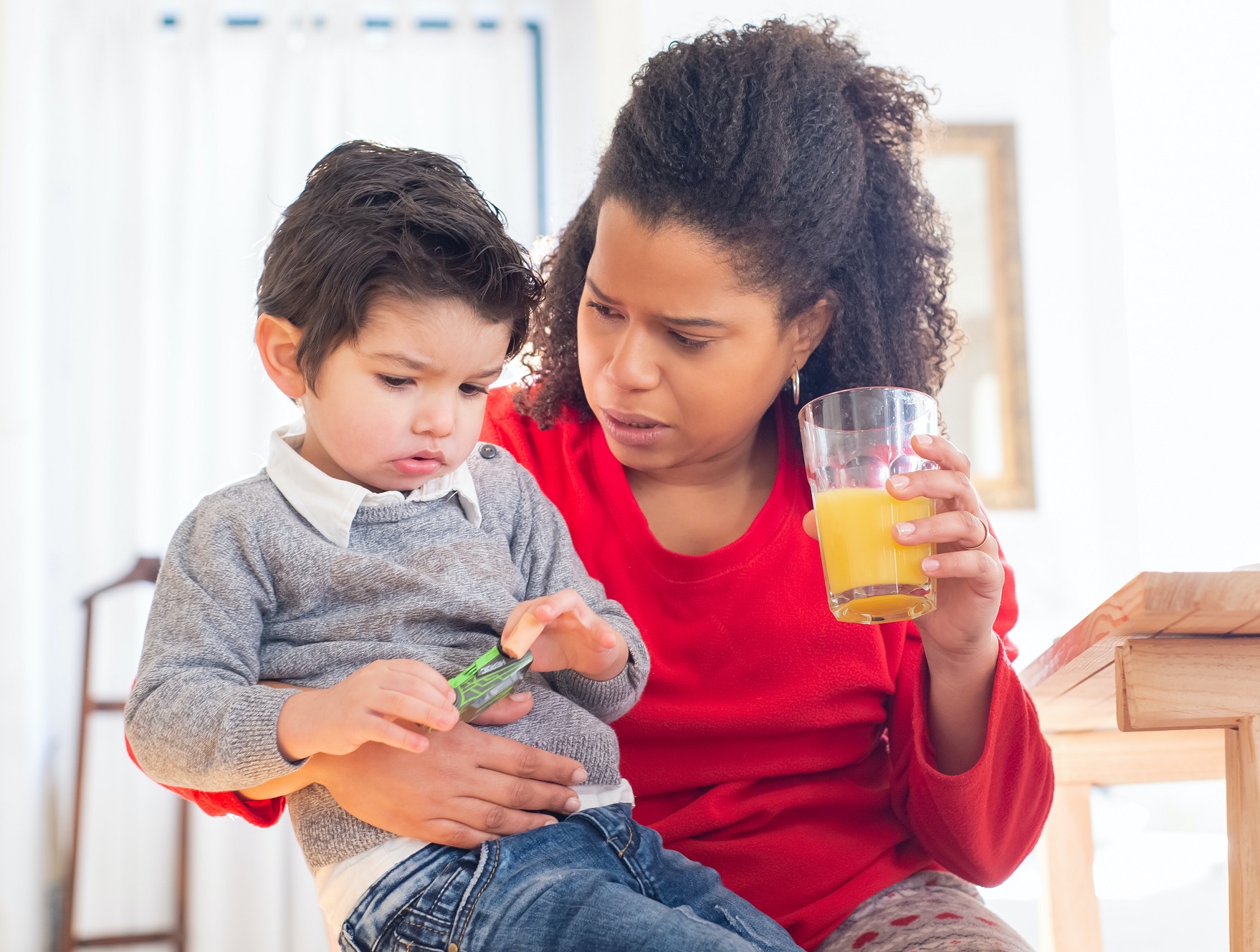 Woman is holding small sad kid next to her and talking with him.