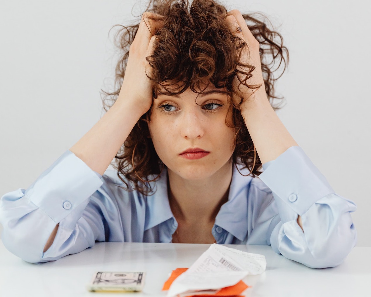 Woman wearing blue shirt is seating on the table with sad face