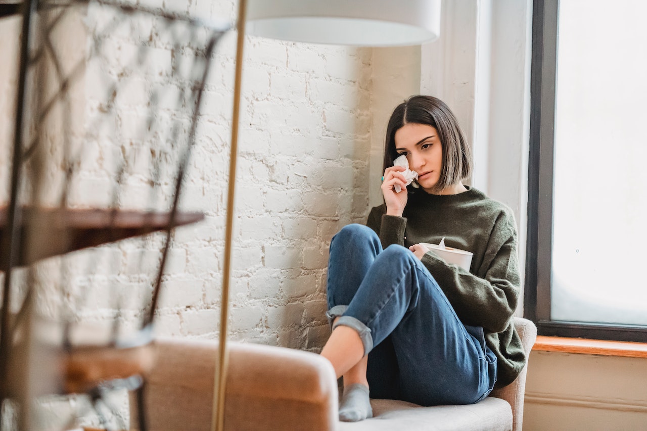 Young girl is seating on the bed and crying.