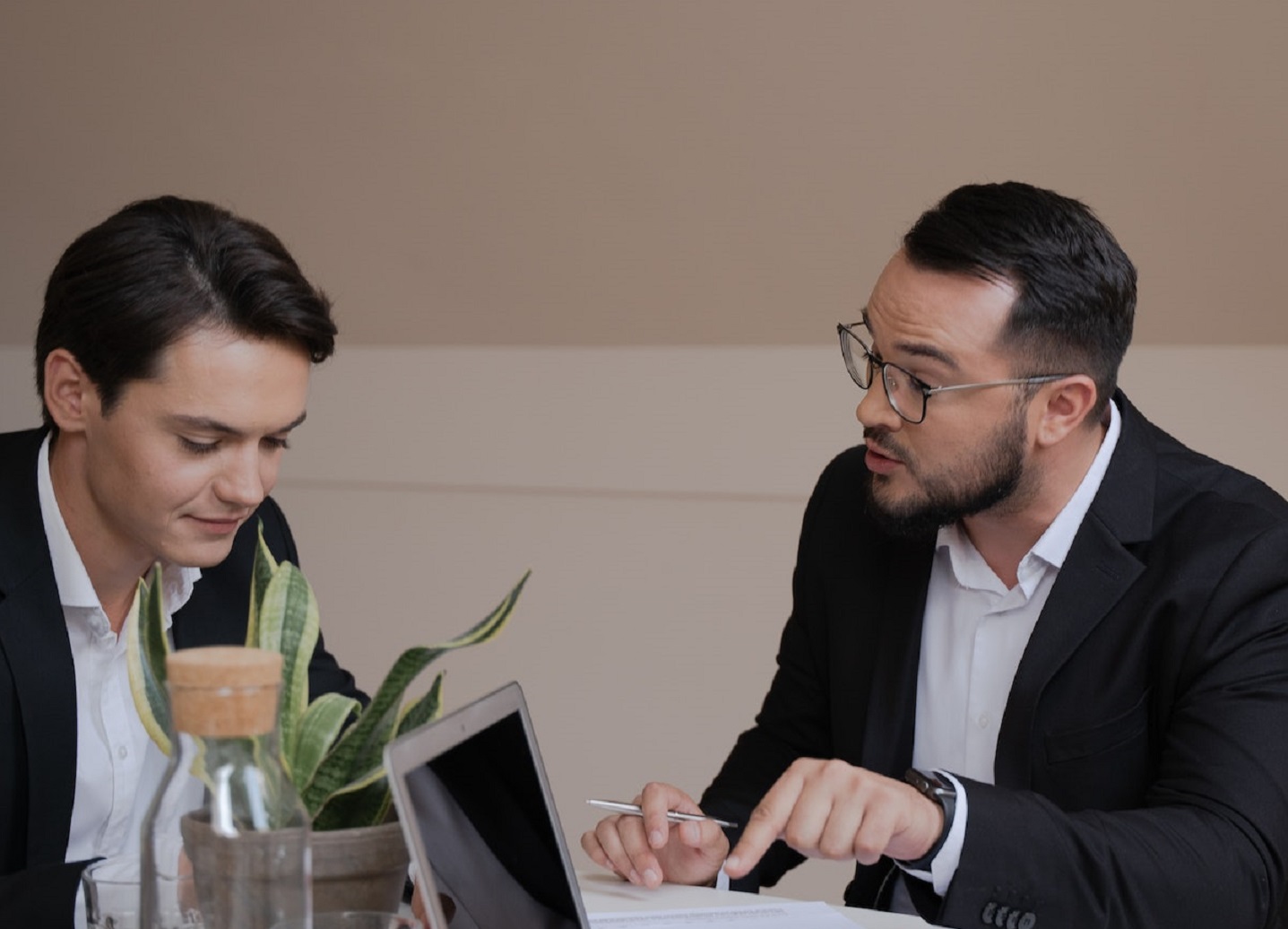 Two man in black suits are having a conversation in office.
