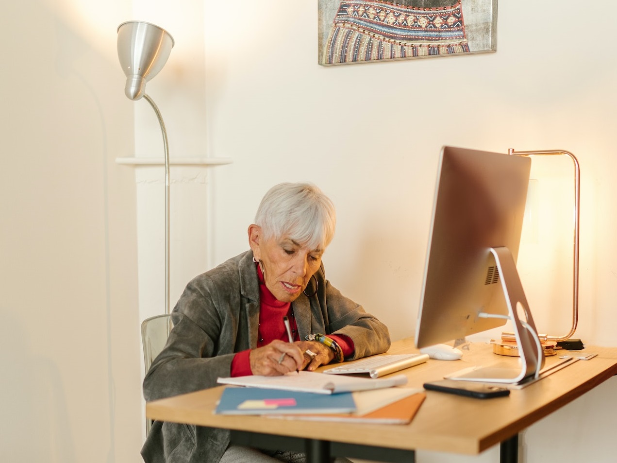 Senior woman is seating and working at her desk at office.