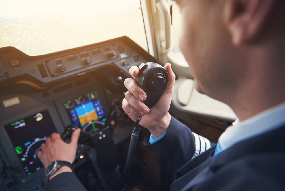 pilot in plane cockpit speaking to passengers