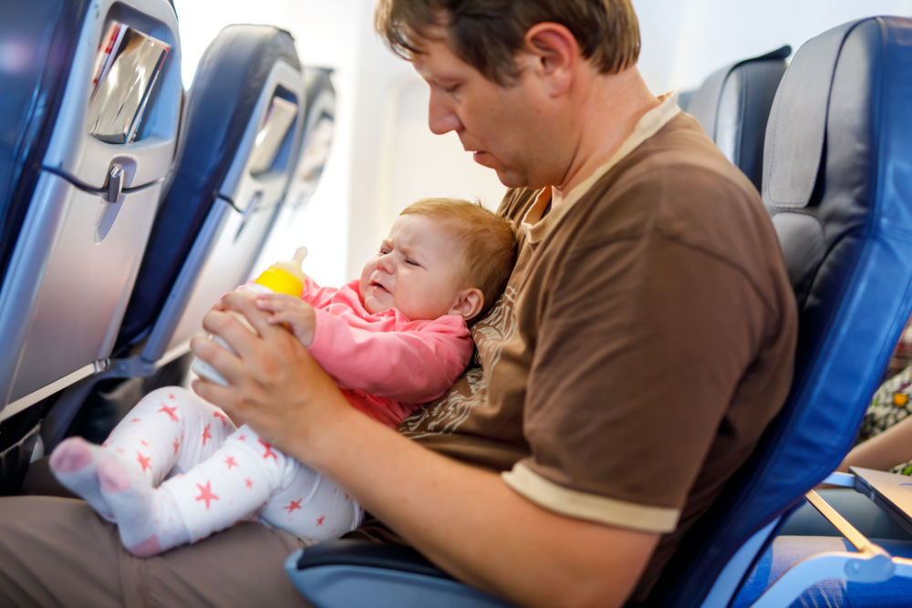 Father holding his crying baby daughter during flight on airplane