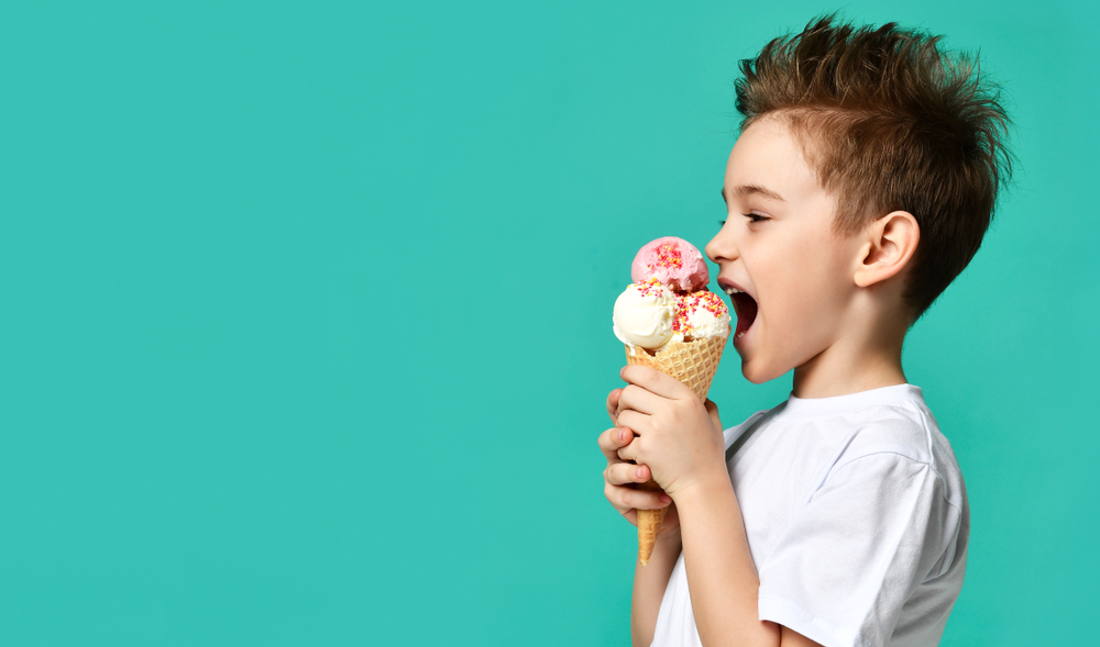 Boy eating ice cream cone wearing white t-shirt looking left