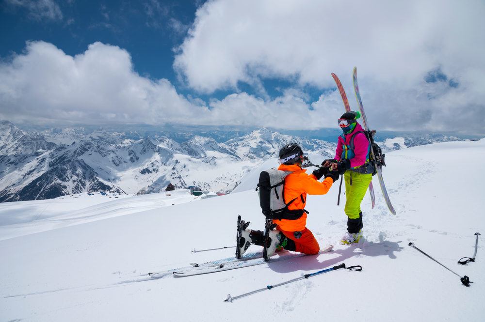 A man skier makes a proposal to marry his girlfriend high in the mountains in winter