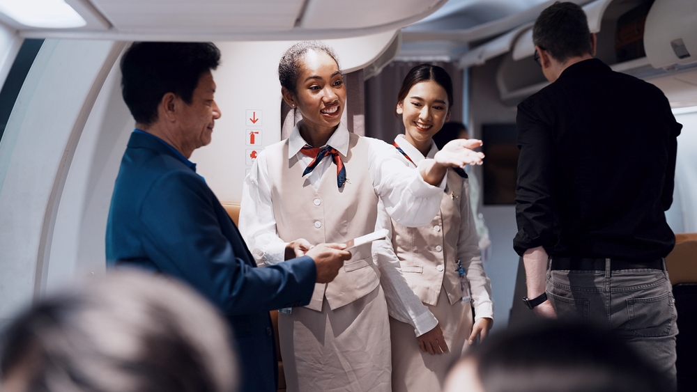 Cheerful black fight attendant and cabin crew assistant checking travel tickets