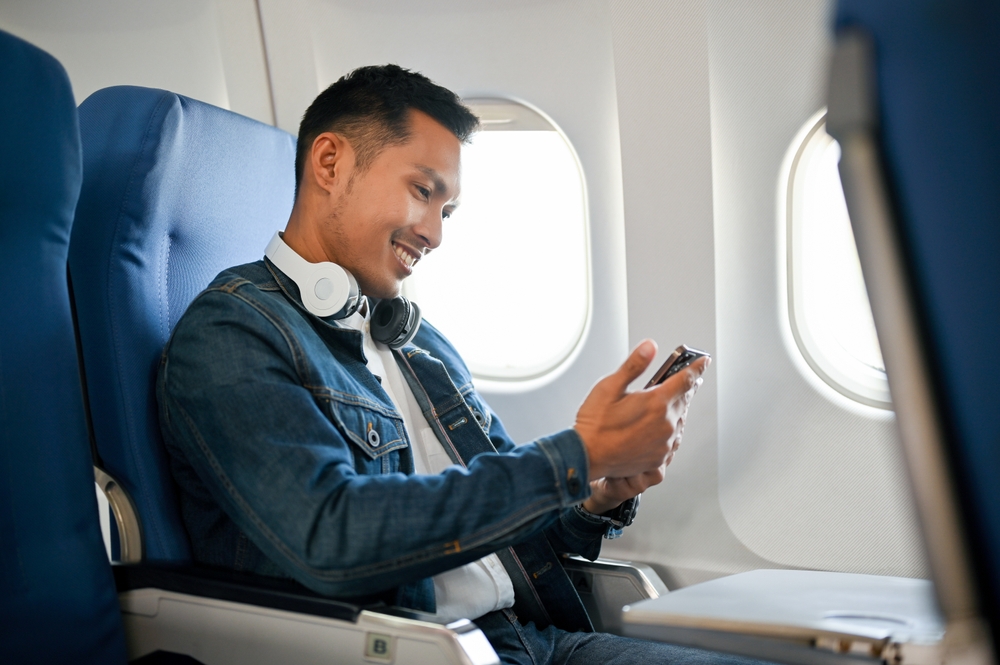 adult Asian male passenger using his smartphone during the flight