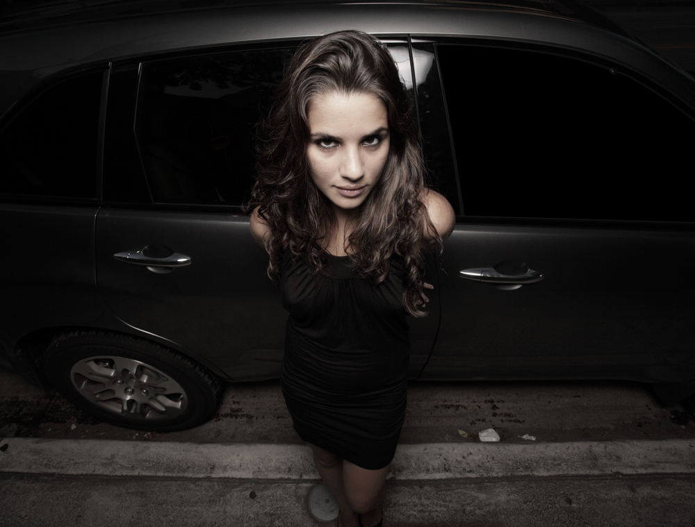 Woman in front of a car at night wearing black dress