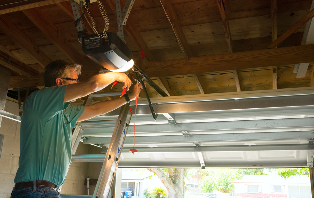 Professional automatic garage door repair service technician man working on a ladder