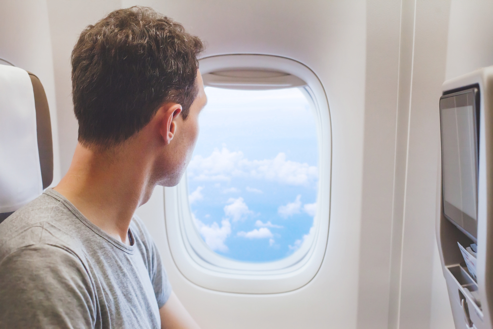 teenager passenger traveling on plane  looking at the  window