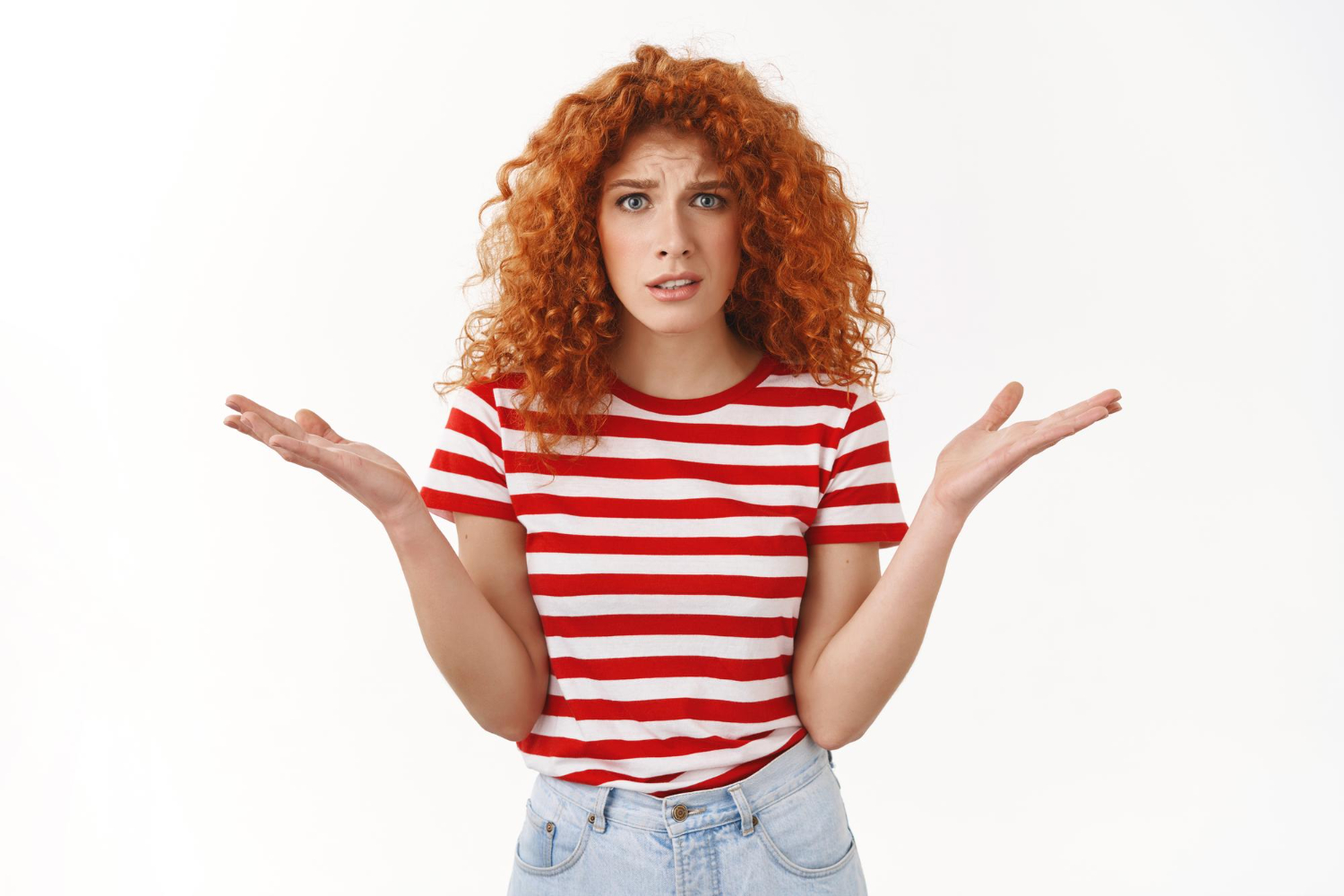 Young redhead curly haired girl is standing with confused face.