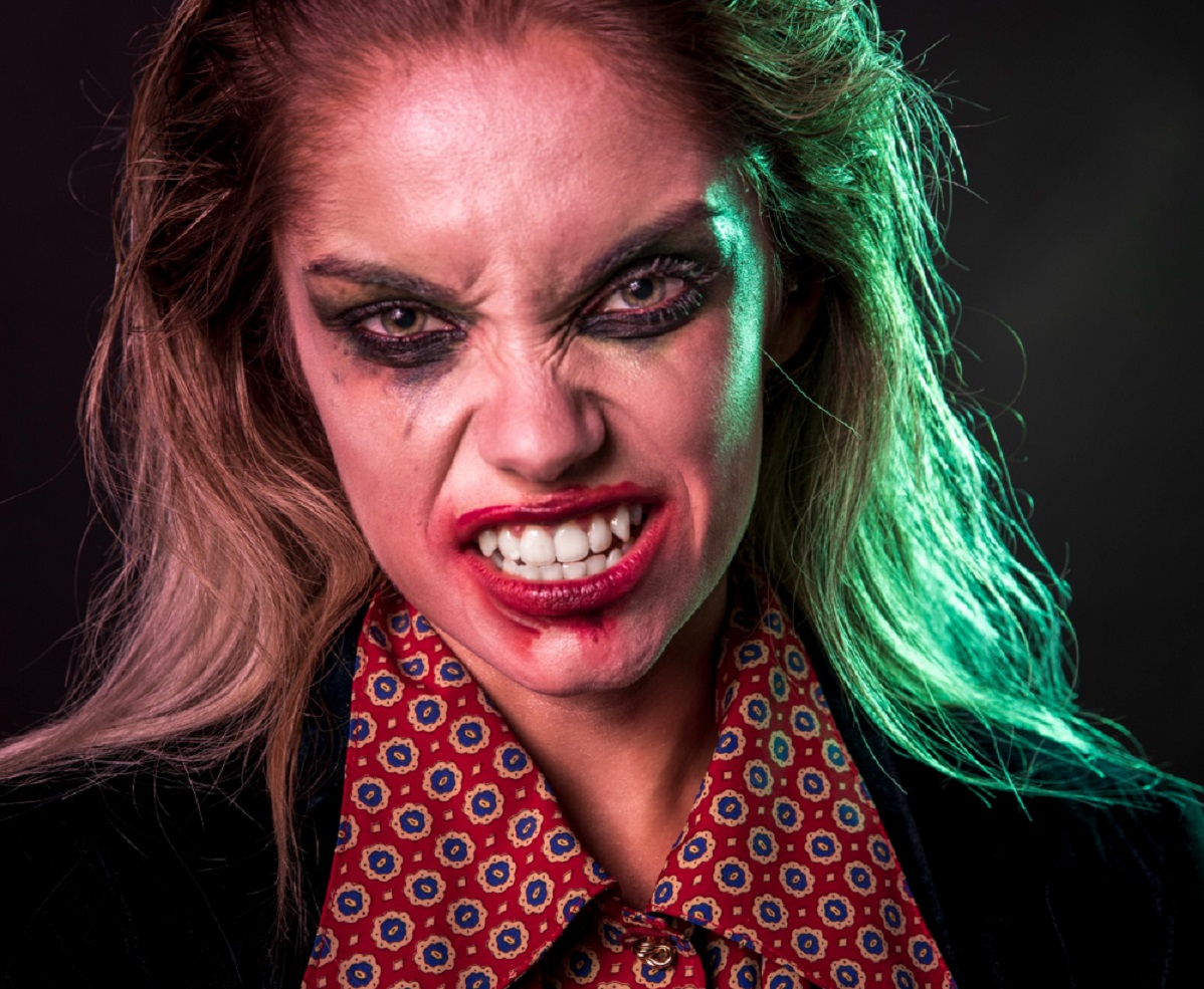 Young woman is showing her teeth like vampire.