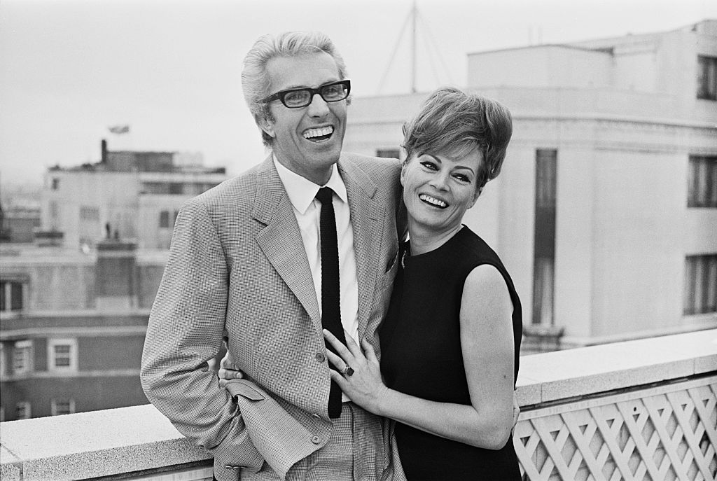 Actress Anita Ekberg and husband on a roof top hugging looking at the camera