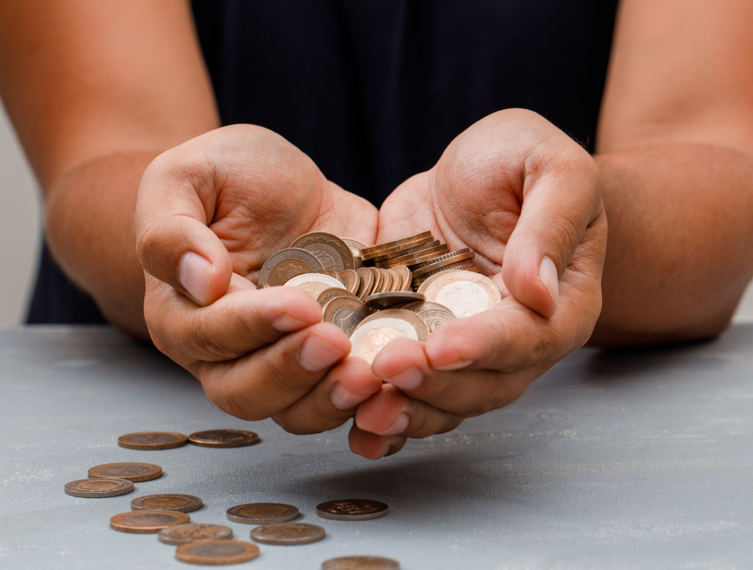 Woman wearing black dress is holding pile of coins at her hands.