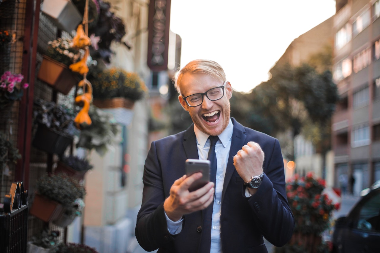 Young man is looking at his phone and smiling ,having a happy face.