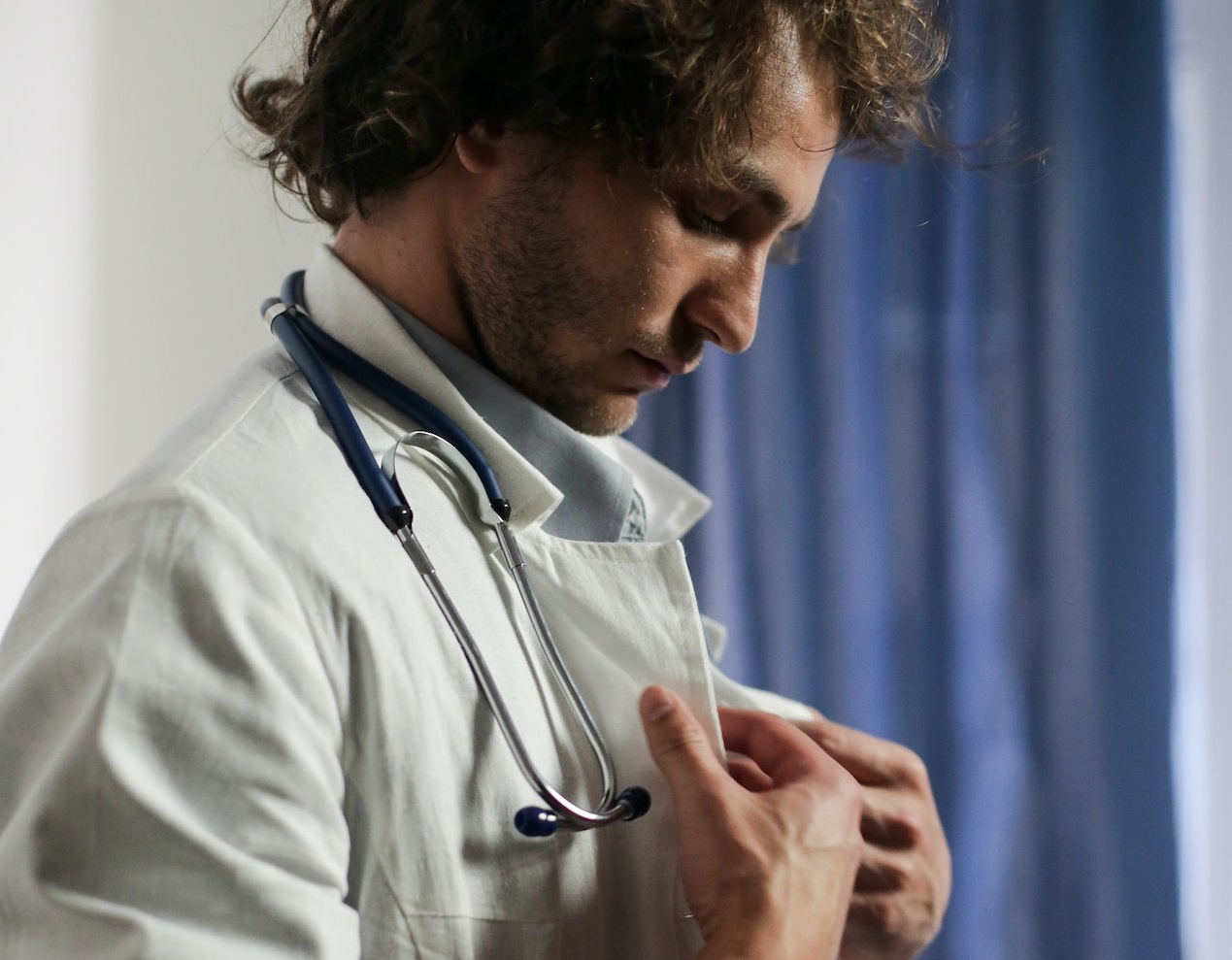 Man wearing white shirt is dressing a white doctor's coat.