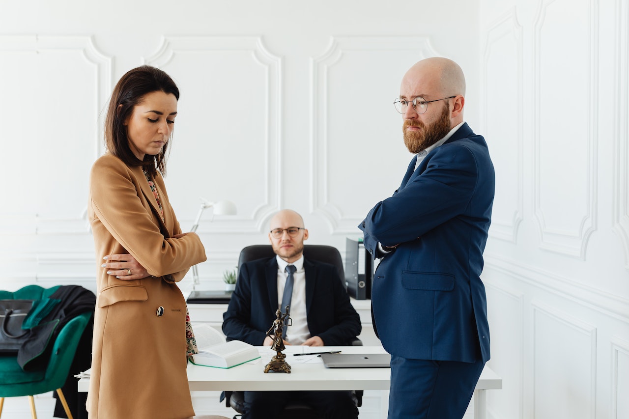 Woman is looking upset standing next to a two man at office.