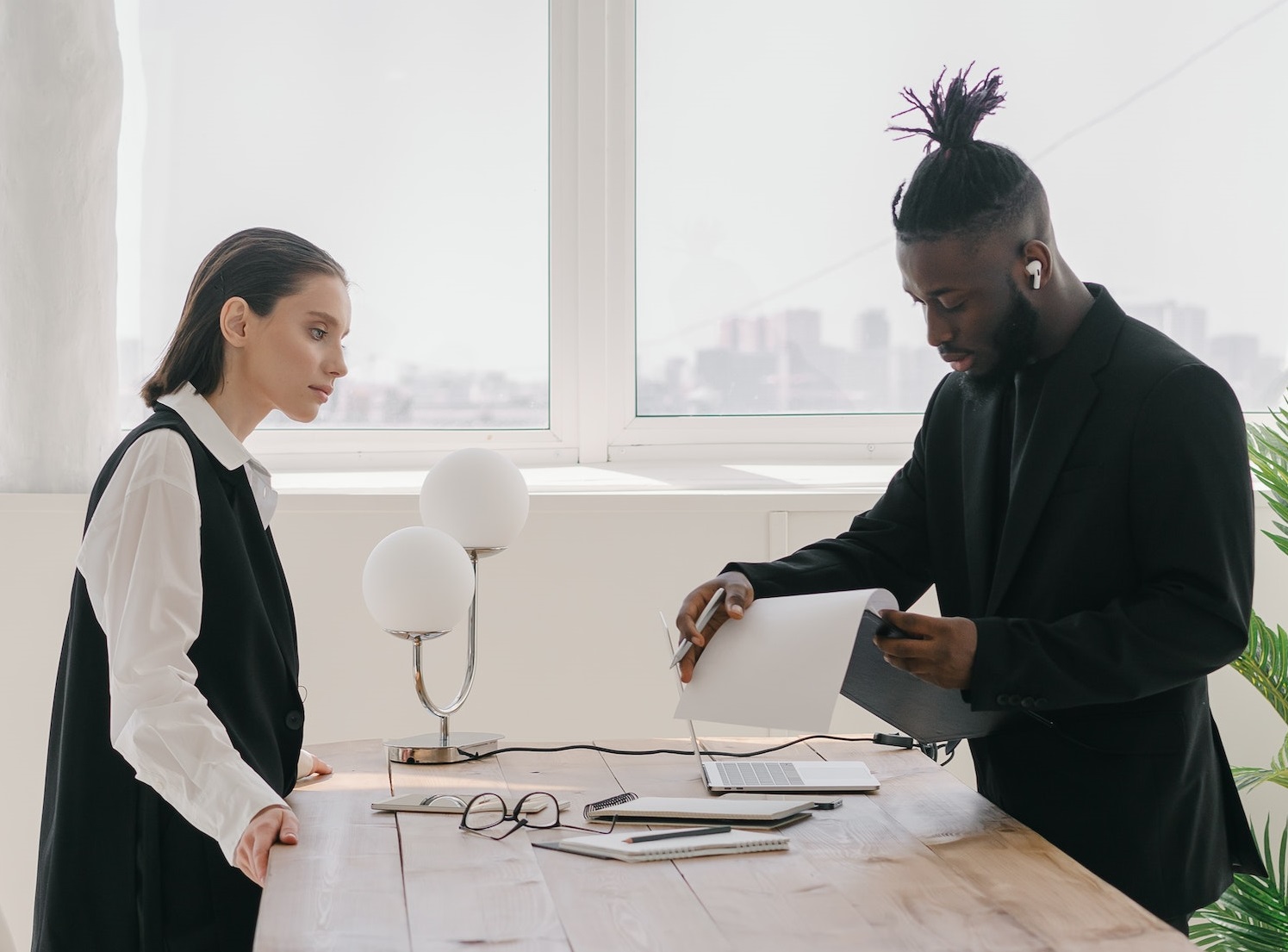 Young black man is looking at files standing with woman at his office.
