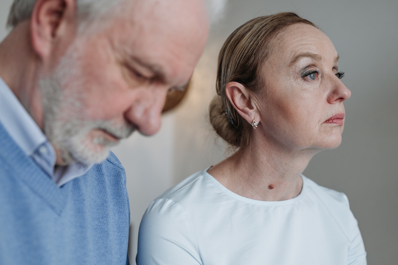 Worried woman is seating next to a worried man ,looking down.