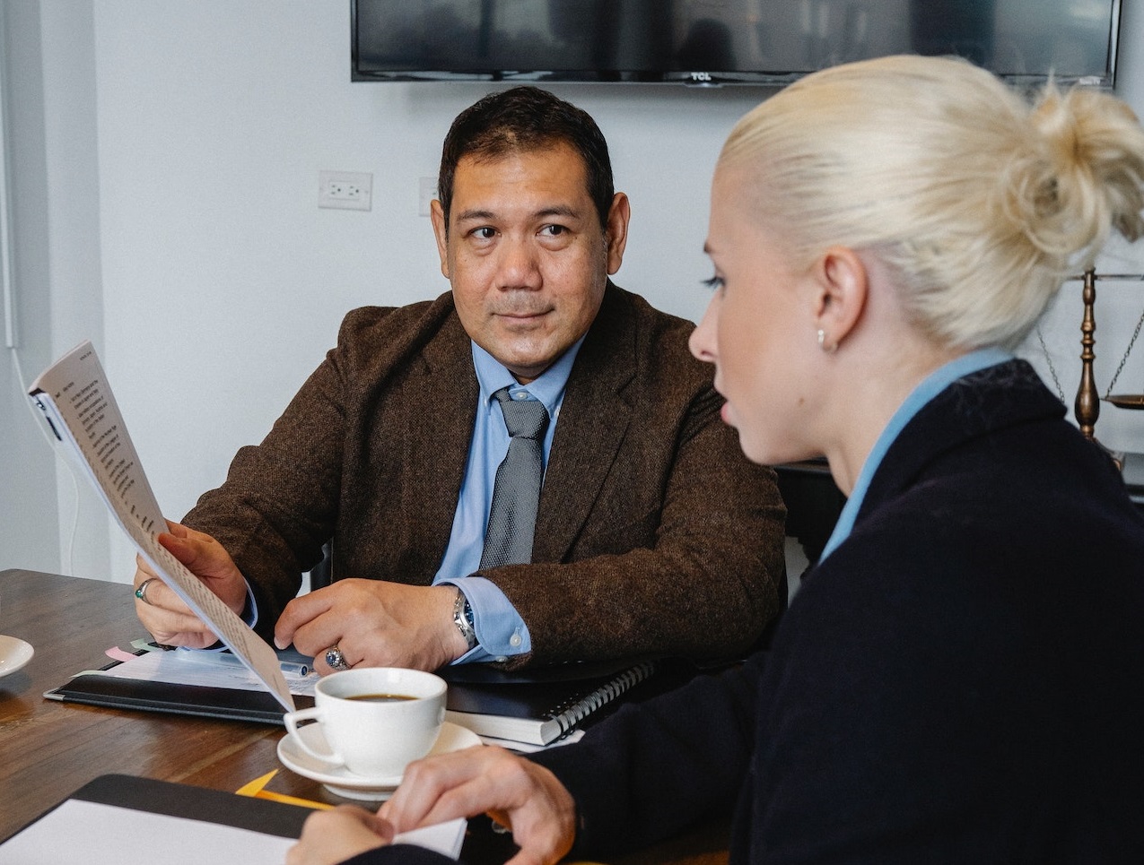Young woman is talking with a man holding documents at office.