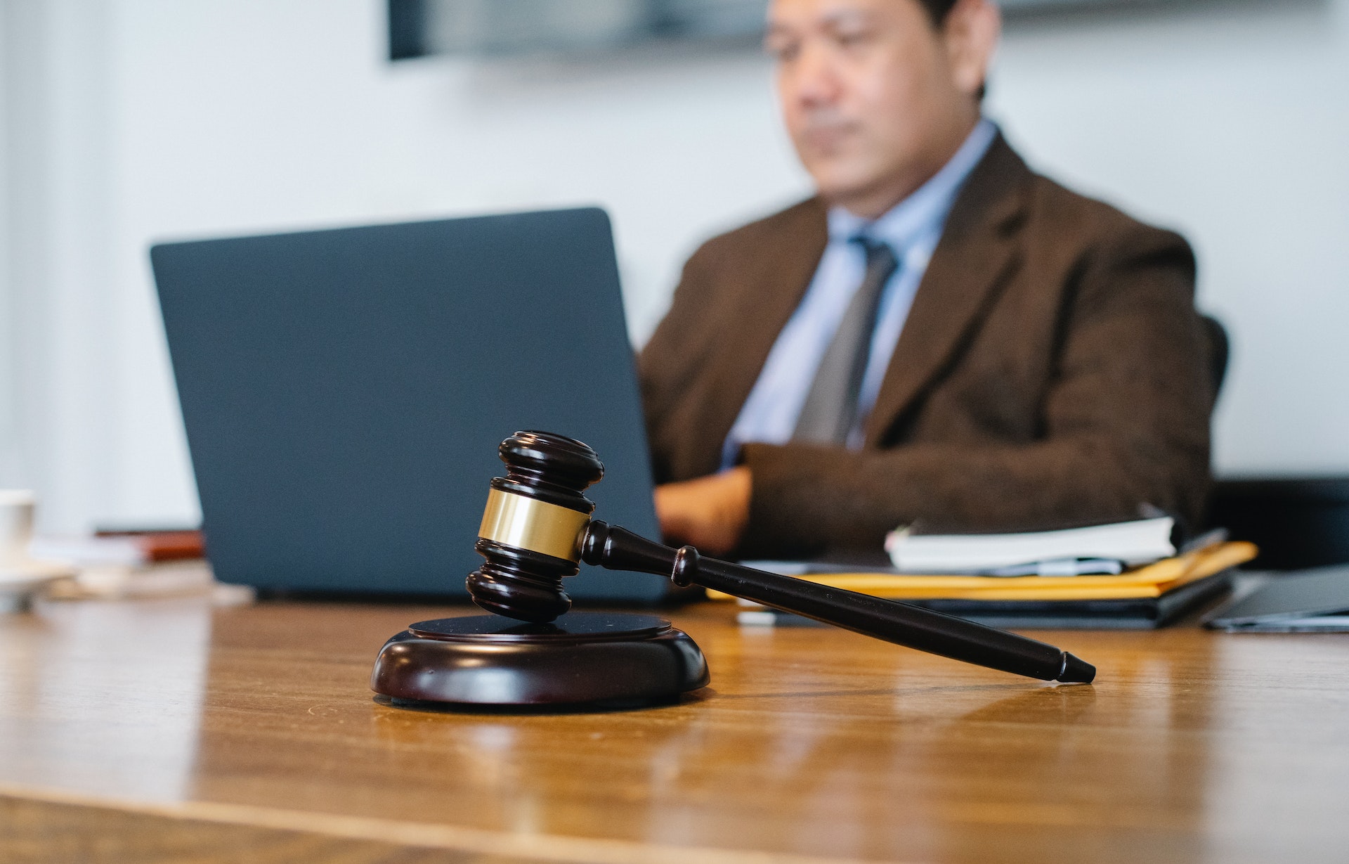 Man is seating on the desk in front of his laptop at court house.