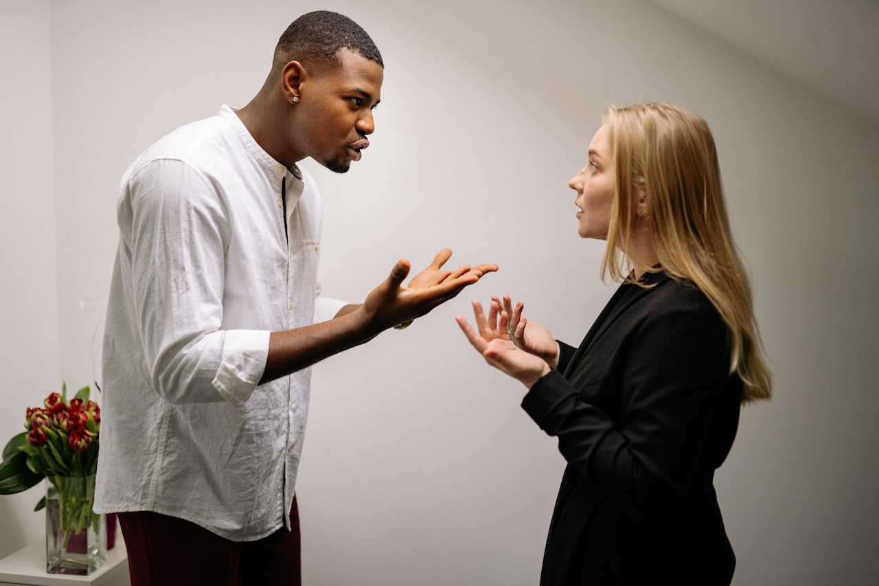 Blonde woman is arguing with tall young black man at office.