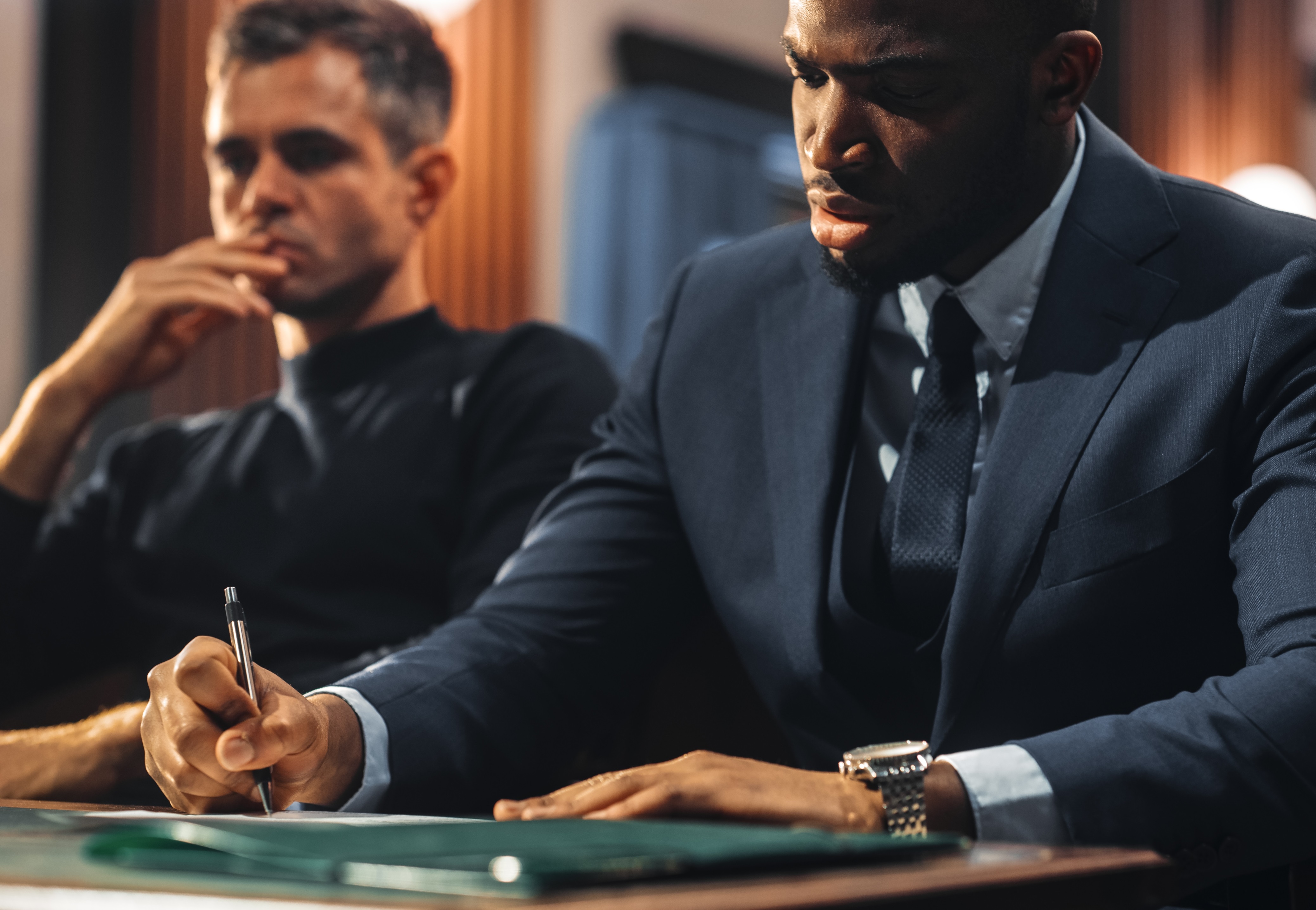 Man is listening and talking to his lawyer in black suit at courtroom trial.