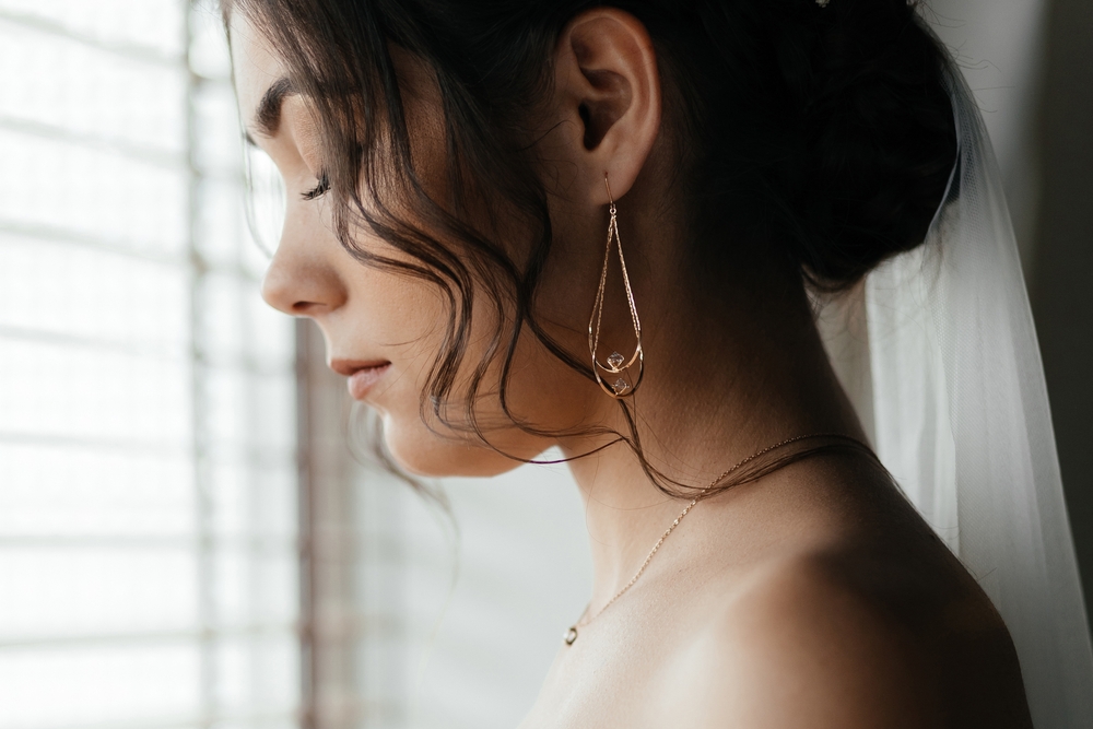 Sad bride in wedding dress and jewels at home